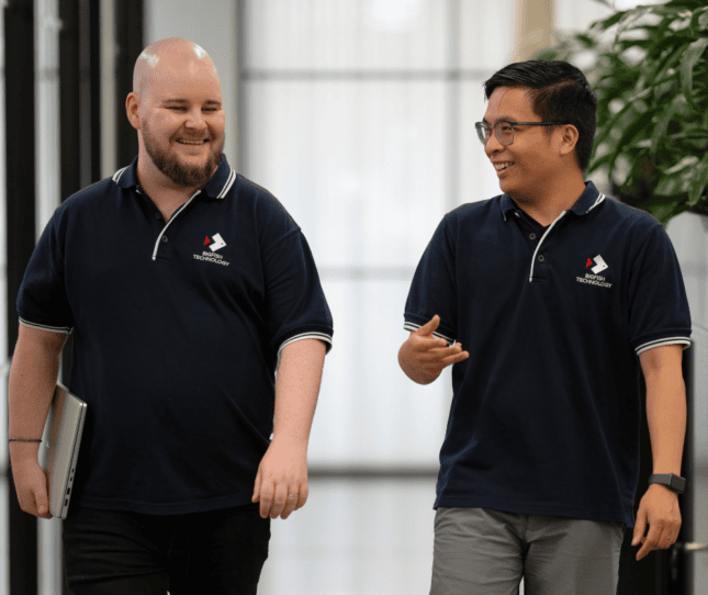 Two smiling team members in black polo shirts at Bigfish office.