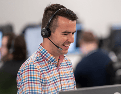Customer support agent with headset providing assistance in a busy call center.