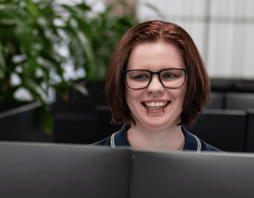 Friendly woman with glasses working at a customer service desk.