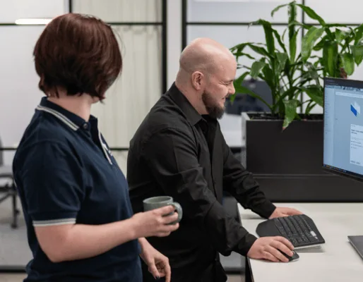 Team collaboration in a modern office environment with two professionals discussing work on a comput.
