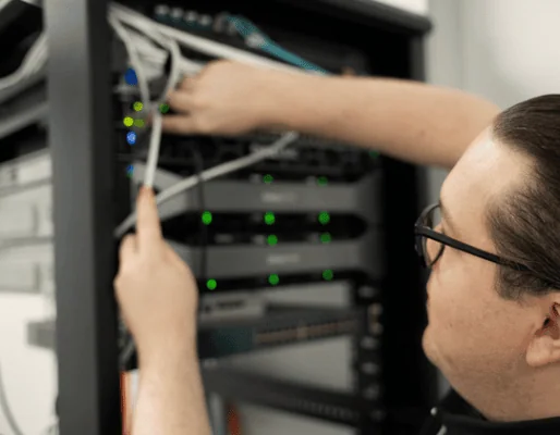 Network technician troubleshooting server connections in data center.